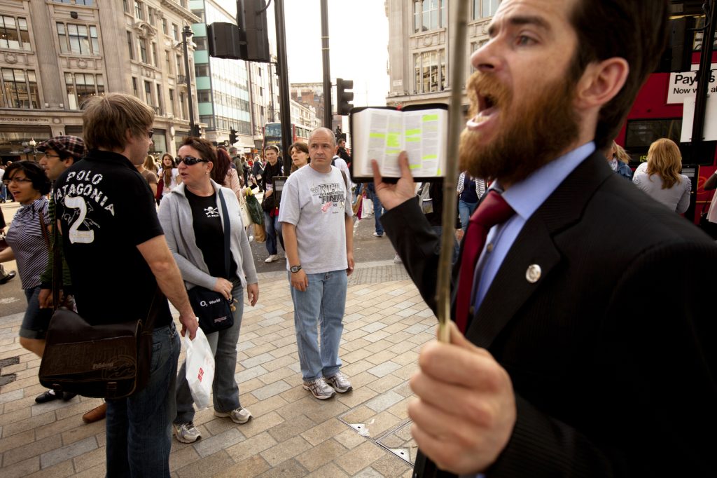 "London, UK - May 6, 2011: An Evangelical street preacher reads from a bible, occasionally stopping to shout personally directed remarks at bewildered and at time aggravated pedestrians in the busy Oxford street shopping district of London."